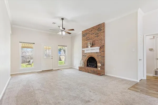 a view of a livingroom with a fireplace a ceiling fan and windows