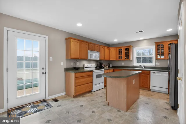 a kitchen with stainless steel appliances granite countertop a refrigerator a sink a stove top oven and a refrigerator