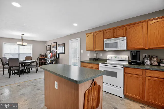 a kitchen with stainless steel appliances granite countertop a stove a sink a microwave a dining table and chairs with wooden floor