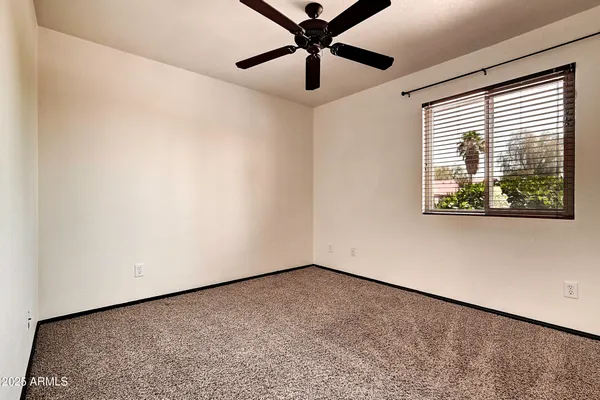 an empty room with a window and a ceiling fan