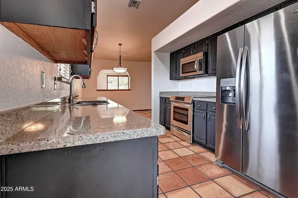 a kitchen with stainless steel appliances granite countertop a sink a microwave and a refrigerator
