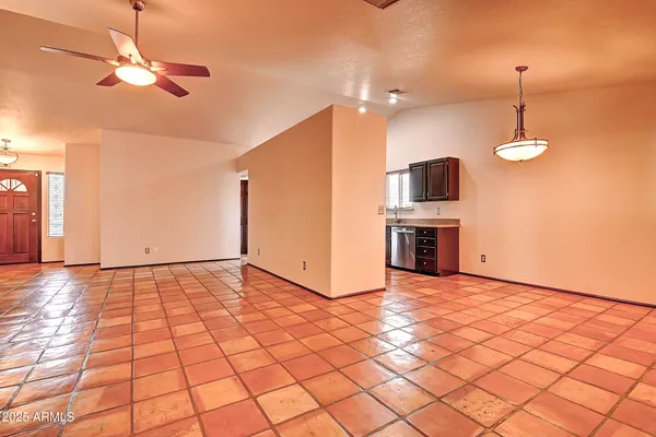 a view of an empty room with a fireplace and a chandelier fan