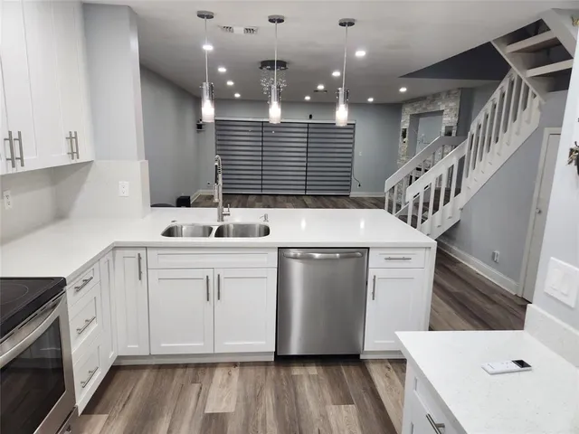 a kitchen with a sink and dishwasher with white cabinets