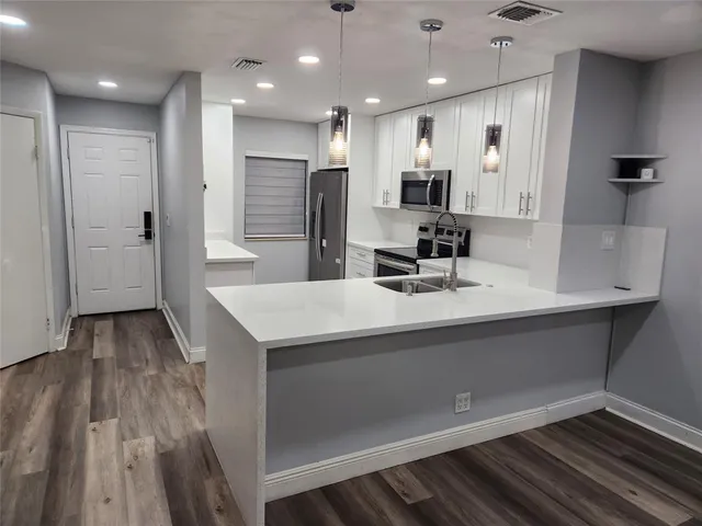 a kitchen with kitchen island a sink appliances and cabinets