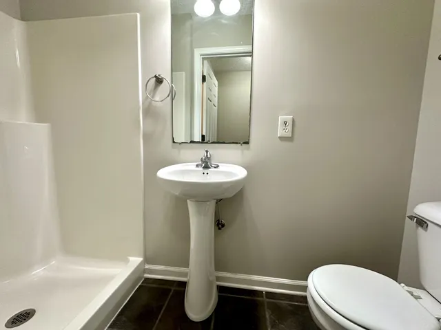 a bathroom with a sink a toilet and shower