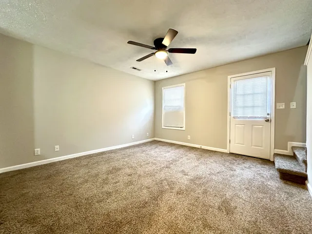 an empty room with windows and ceiling fan