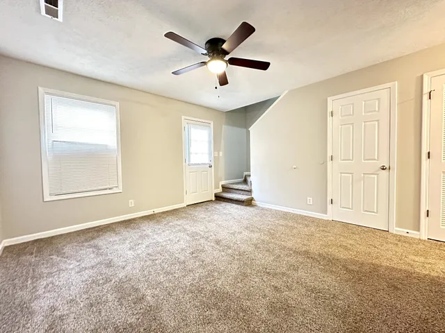 an empty room with ceiling fan and windows
