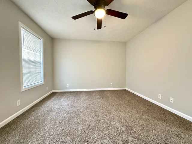 an empty room with a ceiling fan and window
