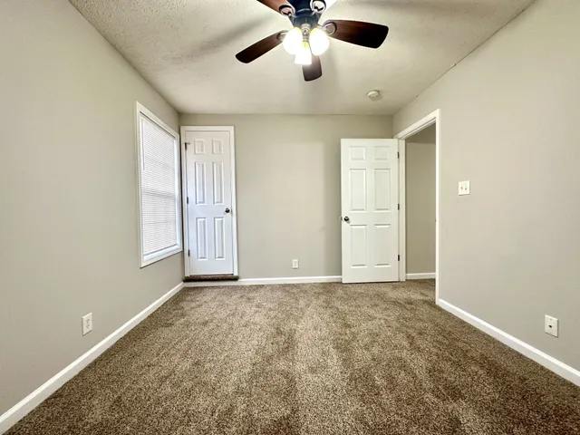 an empty room with a ceiling fan and a window