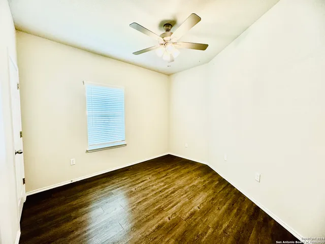 an empty room with a ceiling fan and wooden floor