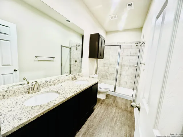 a bathroom with a granite countertop sink a mirror and shower