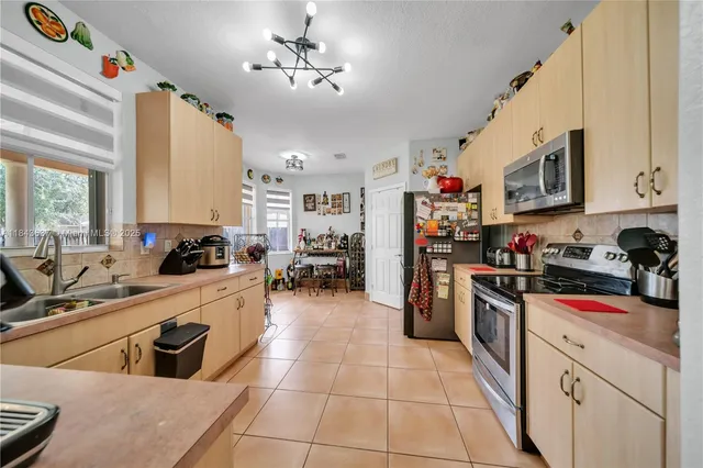 a kitchen with stainless steel appliances kitchen island granite countertop a refrigerator a stove and a sink