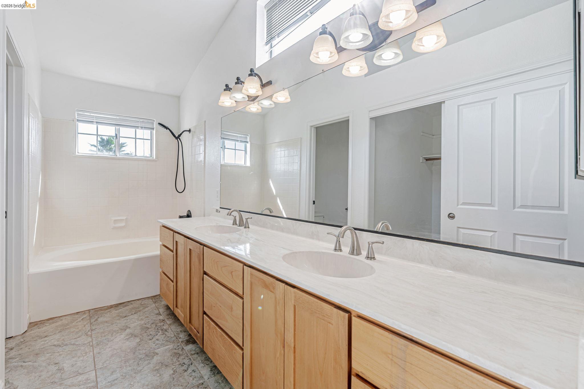 5052 Perry Way Antioch, CA 94531 - Photo 42 of 51 a bathroom with a tub a double vanity sink a mirror and a shower