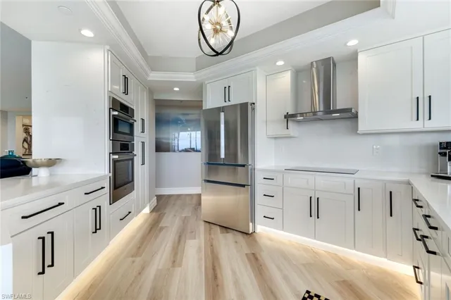 a large white kitchen with a large window a oven and stainless steel appliances