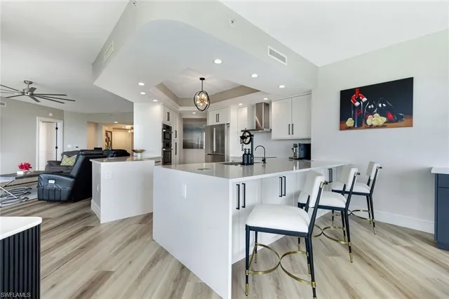 a kitchen with stainless steel appliances kitchen island granite countertop a dining table chairs and a refrigerator