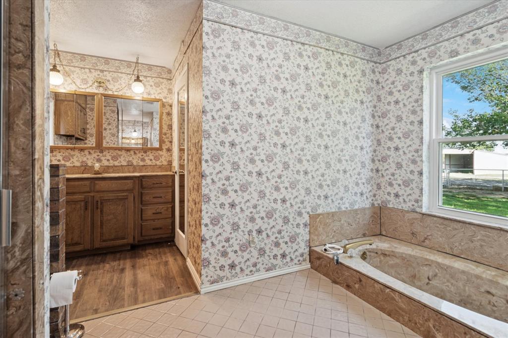 2300 Union Hill Road Sanger, TX 76266 - Photo 19 of 34 a bathroom with a granite countertop sink a bathtub and shower