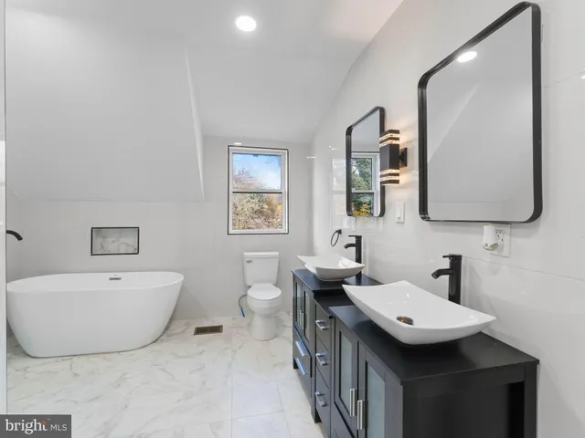 a spacious bathroom with a double vanity sink mirror and bathtub