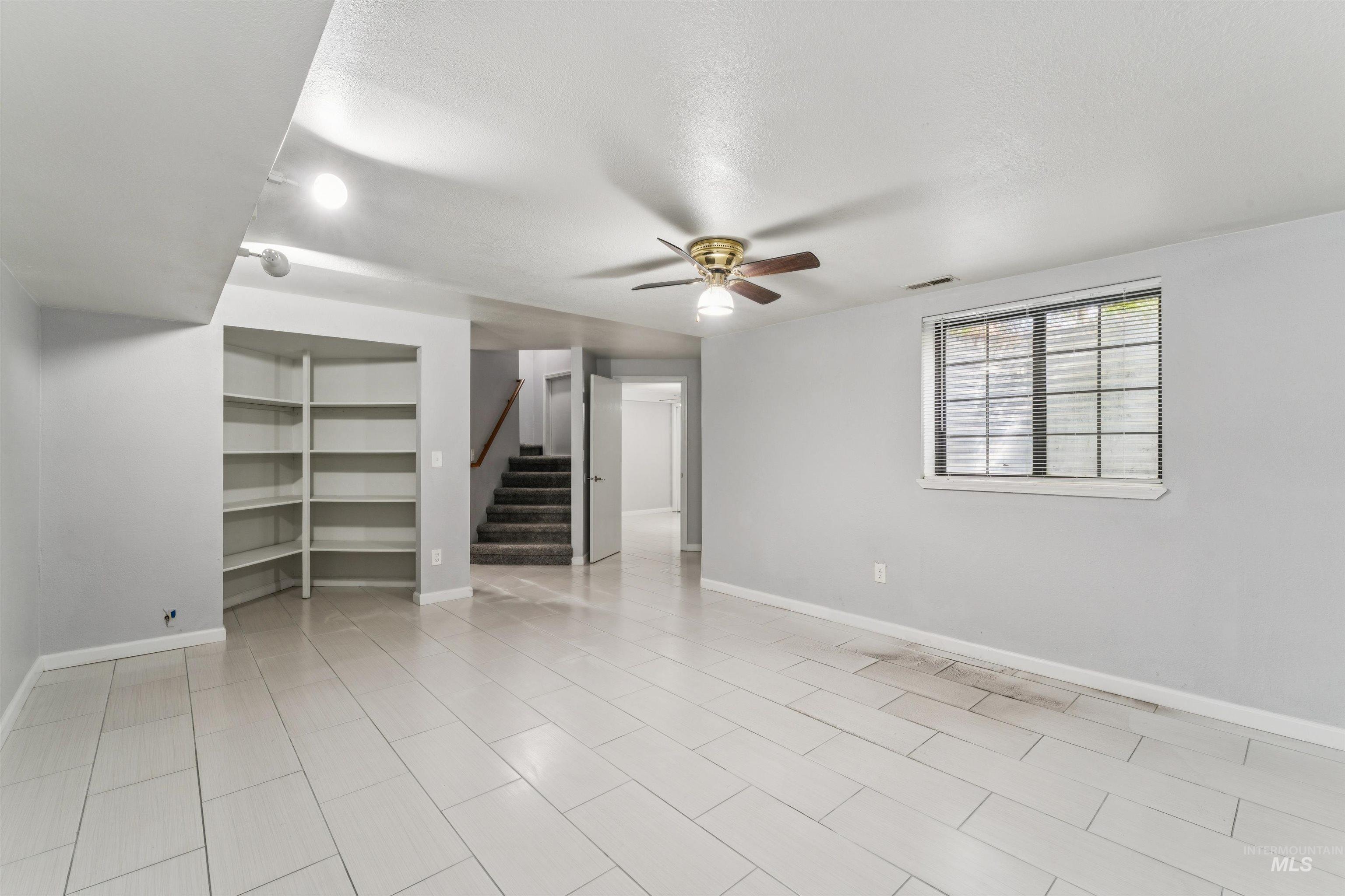 9831 West Ripley Street Boise, ID 83704 - Photo 36 of 47 Spacious garage featuring two overhead doors, concrete flooring, overhead fluorescent lighting, a built-in wooden cabinet, and utility hookups