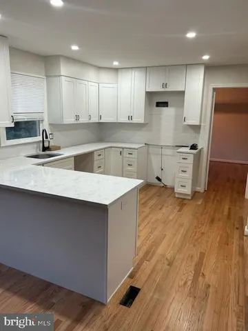 a kitchen with stainless steel appliances granite countertop a sink a stove a refrigerator a microwave oven with white cabinets and wooden floor