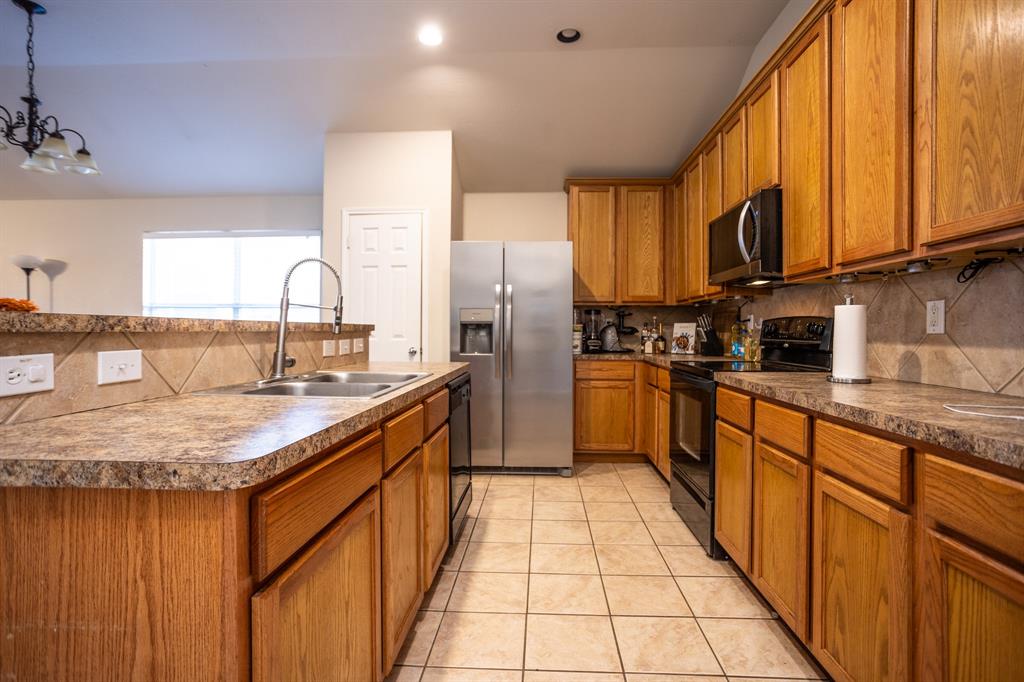 536 Cross Ridge Circle Fort Worth, TX 76120 - Photo 7 of 23 Kitchen with sink, a notable chandelier, decorative light fixtures, a center island with sink, and black appliances