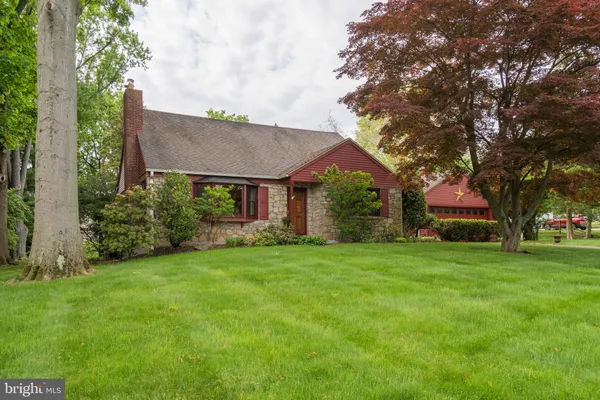 a view of a house next to a big yard and large trees