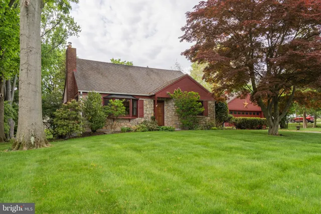 a view of a house next to a big yard and large trees
