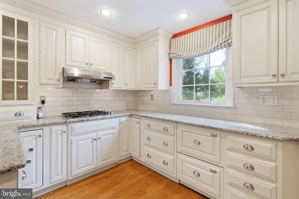 a kitchen with granite countertop white cabinets and window