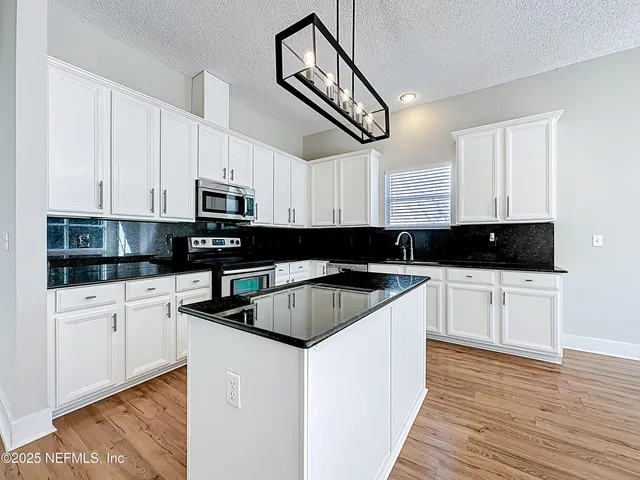 a kitchen with stainless steel appliances granite countertop a stove a sink and white cabinets