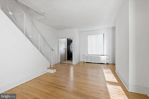 a view of an empty room with wooden floor and stairs