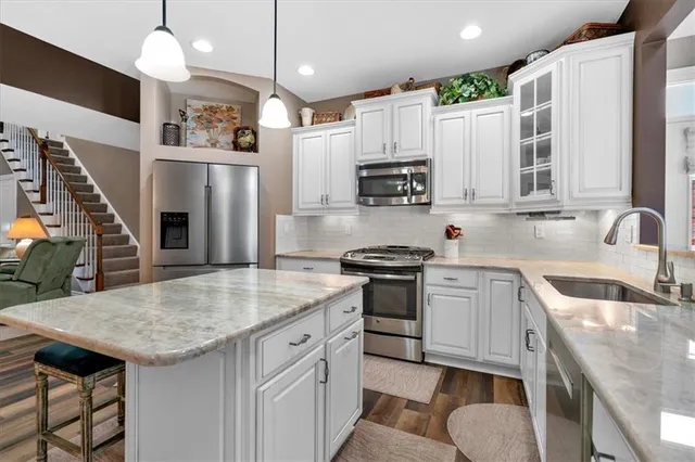 a kitchen with stainless steel appliances granite countertop a sink refrigerator and cabinets
