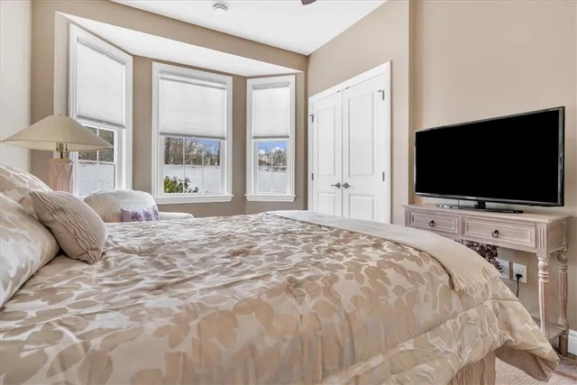 a bedroom with a bed tv and a window