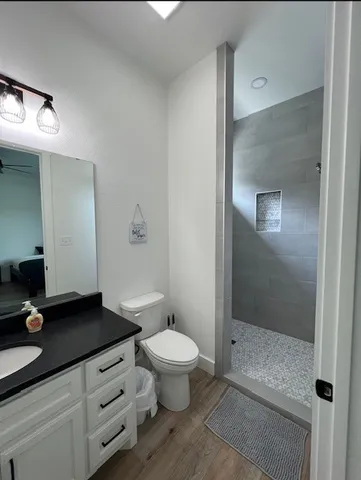 a bathroom with a granite countertop sink a toilet a mirror and shower