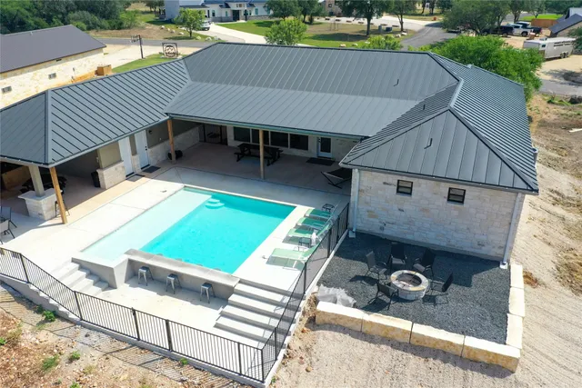 an aerial view of a house with swimming pool and outdoor seating