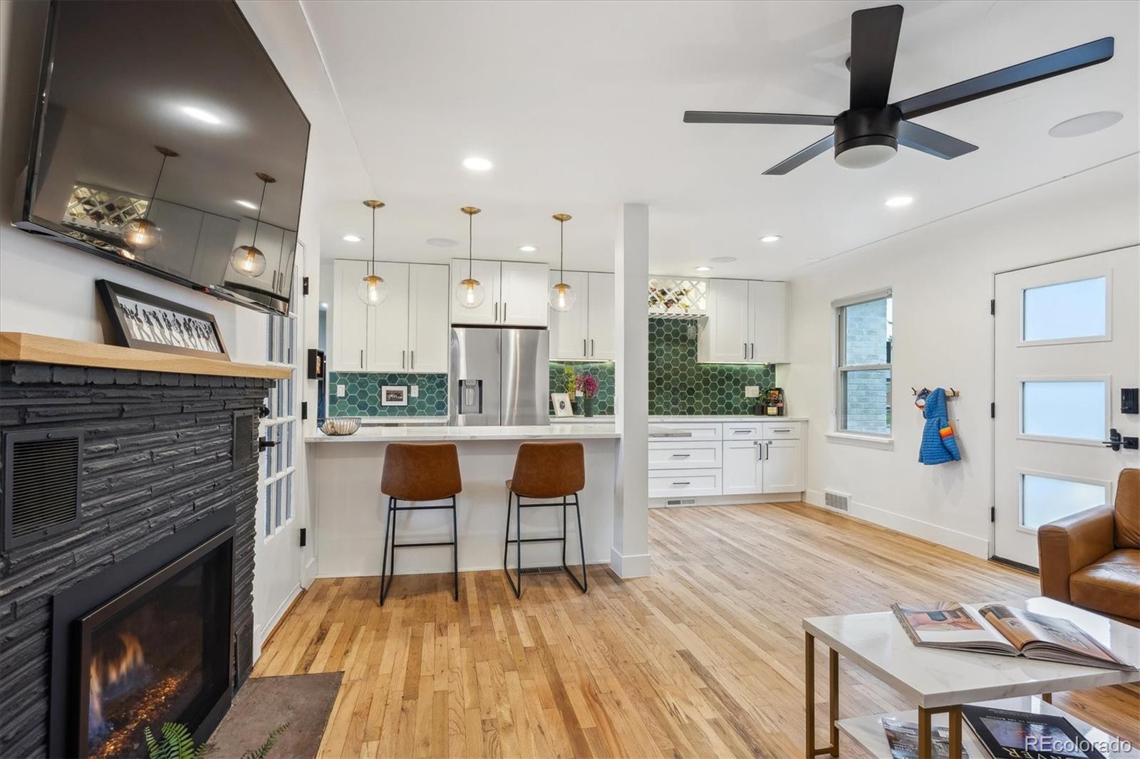 3200 Ames Street Wheat Ridge, CO 80212 - Photo 7 of 46 a living room with stainless steel appliances furniture a fireplace a flat screen tv and view kitchen