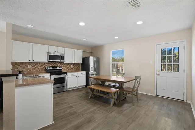 a kitchen with a table chairs microwave and cabinets