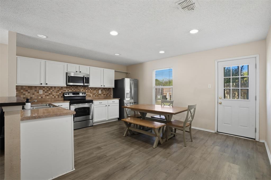 8704 Serenity Way Denton, TX 76210 - Photo 11 of 29 a kitchen with a table chairs microwave and cabinets