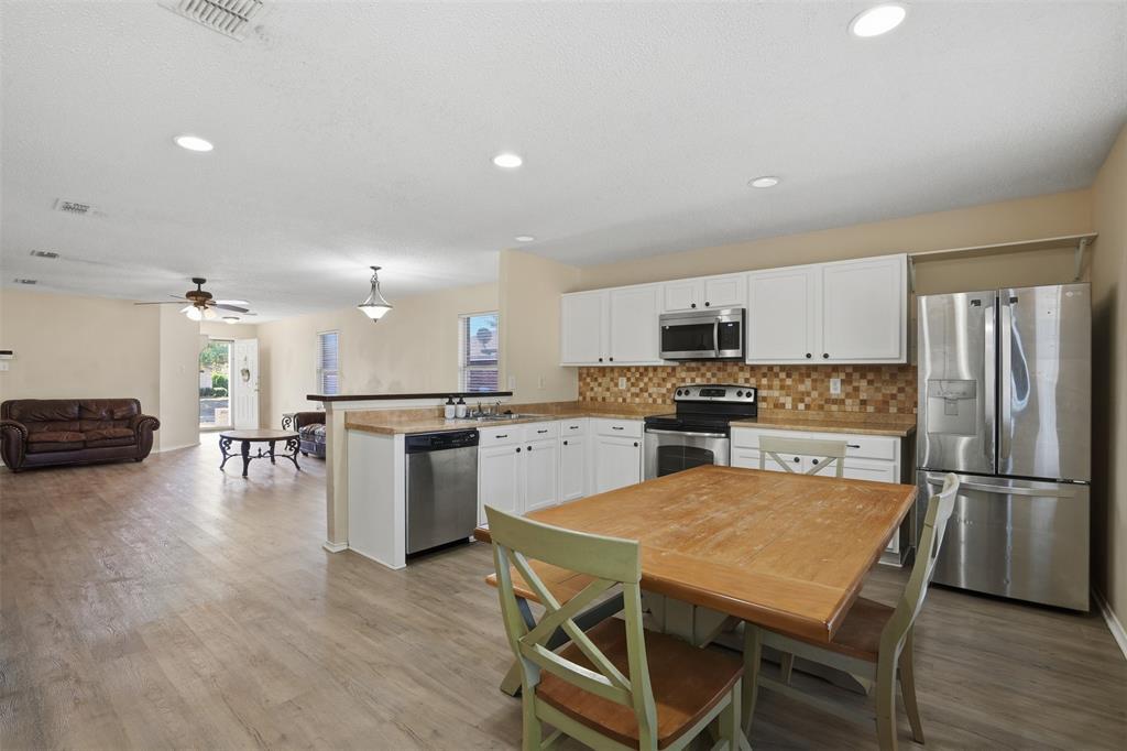 8704 Serenity Way Denton, TX 76210 - Photo 12 of 29 a kitchen with a refrigerator a stove top oven a sink and a island