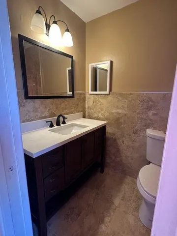 a bathroom with a toilet sink double vanity and mirror