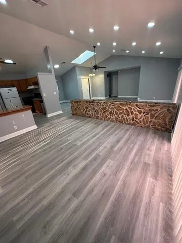 a view of a room with kitchen island stainless steel appliances wooden floor and living room