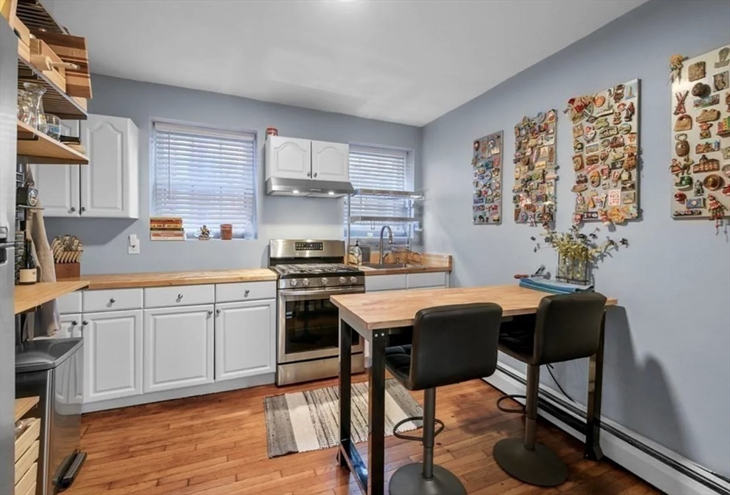 80 Park Street, Unit A Chelsea, MA 02150 - Photo 3 of 11 a kitchen with stainless steel appliances granite countertop a stove top oven a sink a dining table and chairs with wooden floor