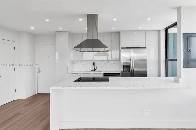 a kitchen with stainless steel appliances a refrigerator a sink a stove a microwave and white cabinets