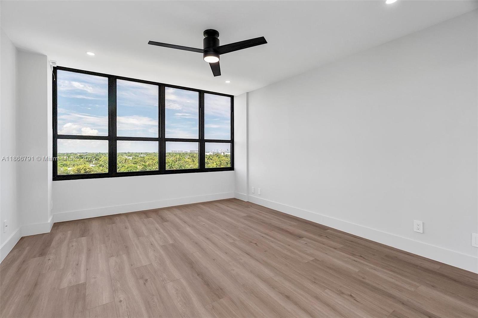 780 Northeast 69th Street, Unit 910 Miami, FL 33138 - Photo 7 of 26 wooden floor in an empty room with a window
