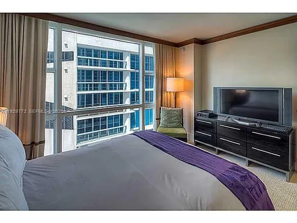 a bedroom with a bed and a flat tv screen on dresser