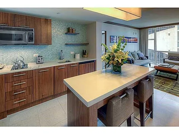 a kitchen with stainless steel appliances kitchen island granite countertop a table chairs in it and a window