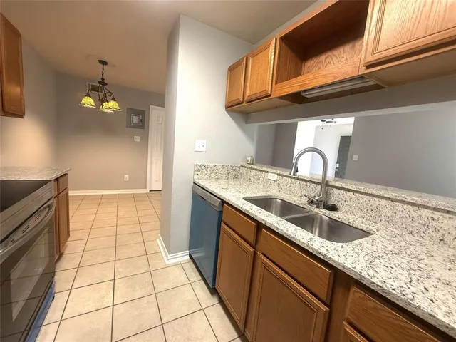 a kitchen with granite countertop a sink a stove cabinets and utility