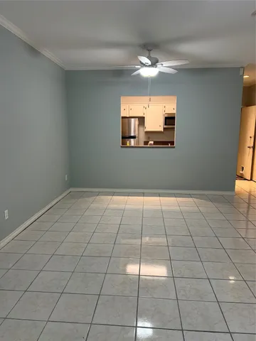 a view of a livingroom with an empty space a ceiling fan and window