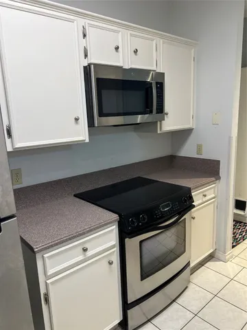 a kitchen with granite countertop white cabinets and black appliances