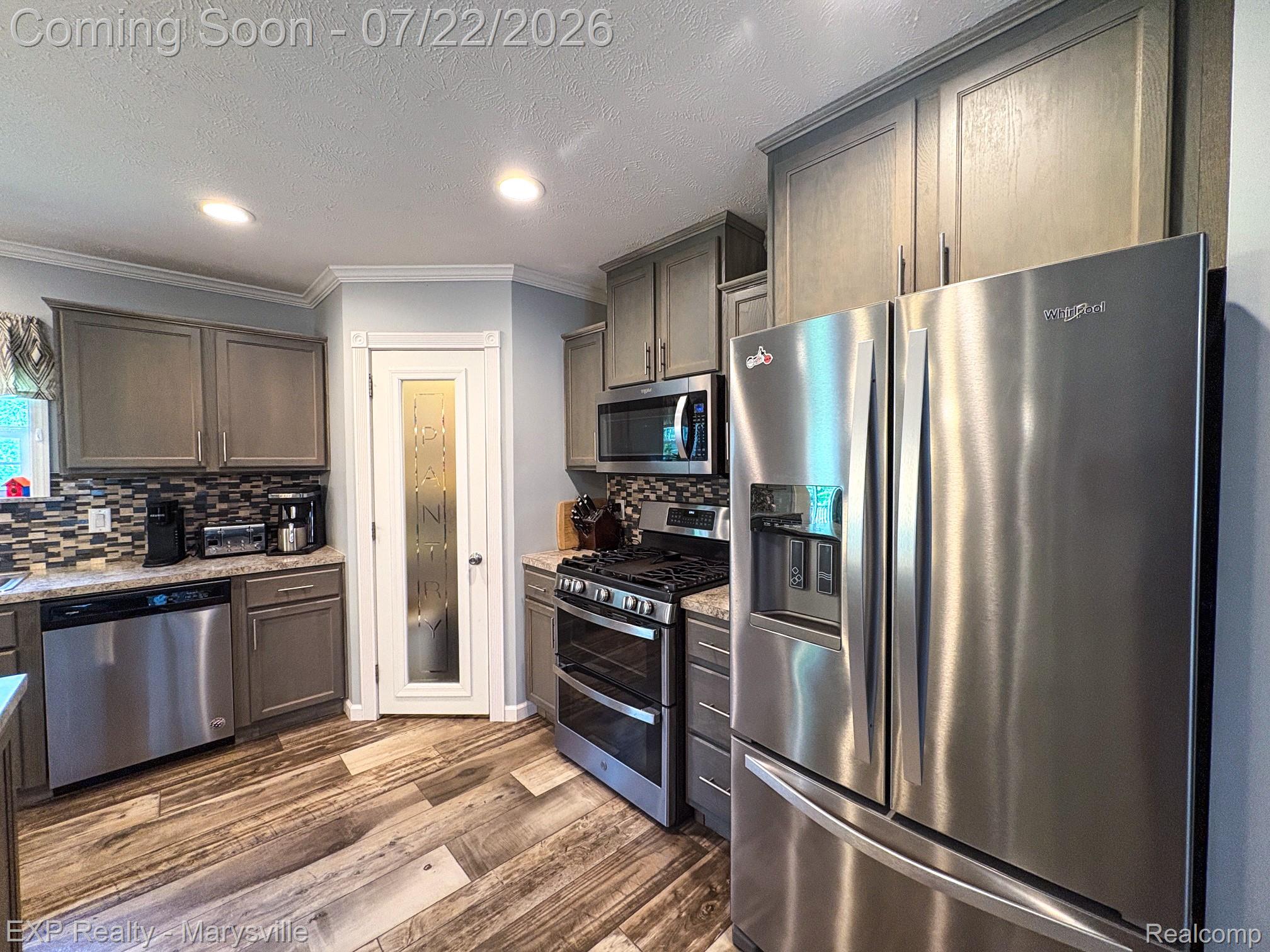 2601 Beach Road Port Huron, MI 48060 - Photo 13 of 34 Kitchen featuring stainless steel appliances, wood-finish flooring, recessed lighting, gray cabinetry, and a pantry with a frosted glass door
