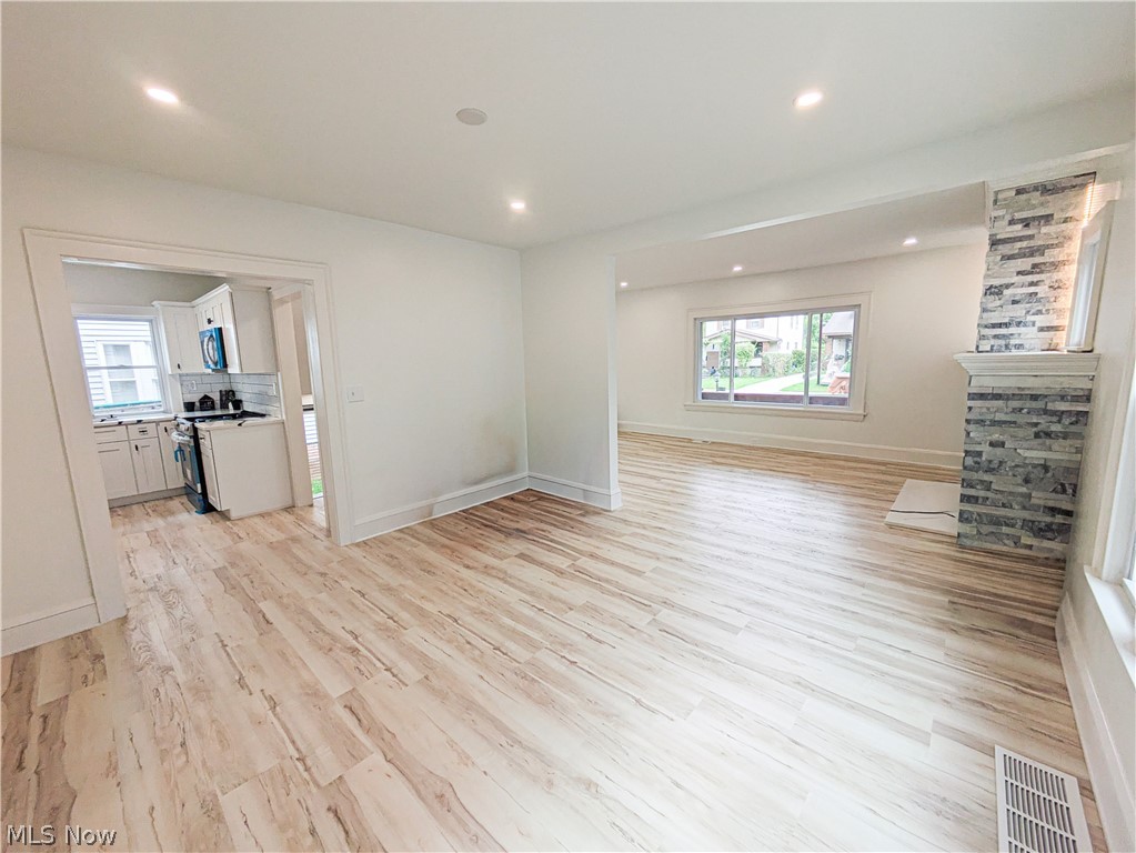 3554 Ludgate Road Shaker Heights, OH 44120 - Photo 12 of 50 Recessed lighting, light wood-finish flooring, white walls, stone veneer fireplace with white mantel, and white kitchen cabinetry