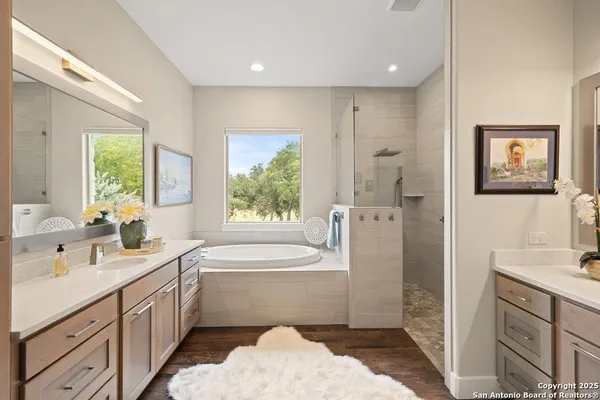 a bathroom with a double vanity sink a large mirror a shower and bathtub